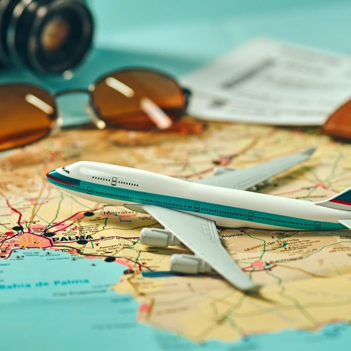Embark on an adventure. Map, plane, camera, glasses and passport on the table. Travel, vacation concept.